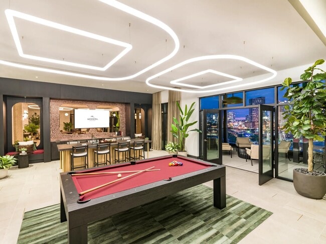 A sky lounge designed to impress—with skyline views, a billiards table, and bar seating perfect for entertaining.