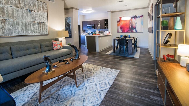 Cocina del apartamento con electrodomésticos de acero inoxidable, comedor y sala de estar con pisos de madera. - Griffis Lakeline Station