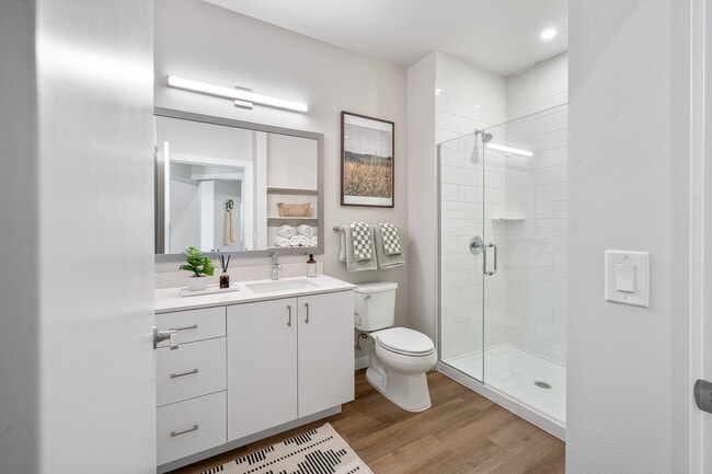 Finish Package I primary bathroom with white cabinetry, white quartz countertops, framed mirror and hard surface flooring