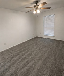 Spacious bedroom with plush carpeting, natural light, and a ceiling fan