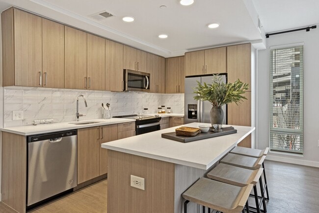 Gourmet Kitchen And Dining Area With White Countertops, Rustic Taupe Cabinets, and Stainless-Steel Appliances