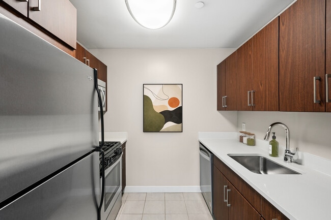 Kitchen with espresso cabinetry, white quartz countertops, stainless steel appliances, and hard surface flooring