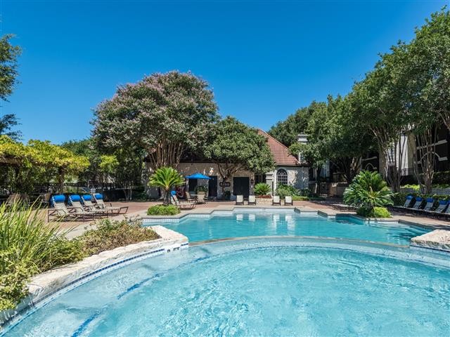 Pool surrounded by lush landscape and poolside seating - Colonnade Apartments