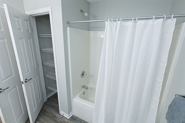 Fresh, clean bathroom with full tub and convenient built-in shelving for extra storage.