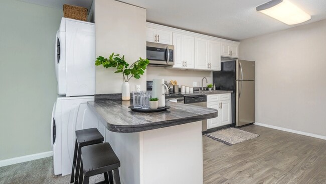 A versatile kitchen with a convenient breakfast bar, perfect for cooking, studying, or folding your laundry. The centrally located full-size washer and dryer is perfectly placed for ultimate convenience. - Alpine Commons