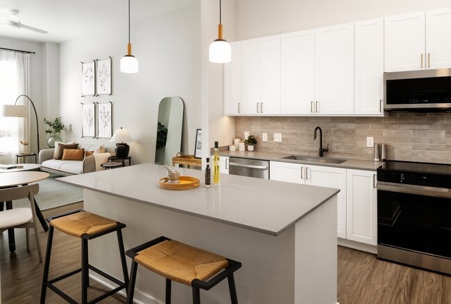 Design Collection I kitchen with stainless steel appliances, grey quartz countertops, white cabinetry, and hard surface flooring - Avalon Annapolis Apartments