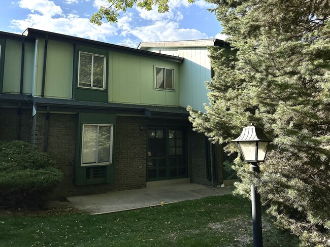Inviting green townhouse with brick accents and lush landscaping. - Char Rose Rental