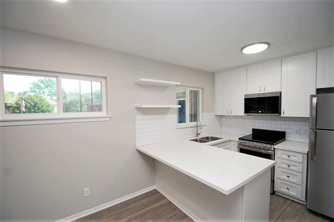 Kitchen with SS Appliances and Quartz Peninsula Countertops - Pine Village Apartments