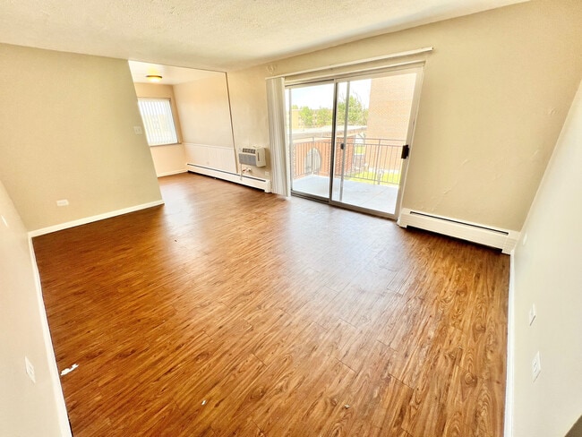 Sala de estar luminosa y acogedora con elegantes pisos de madera, que se abre a un balcón soleado a través de puertas corredizas de vidrio. - Bonneville Apts