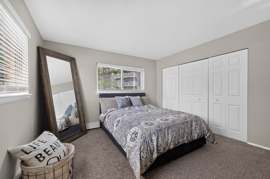 Relax in a spacious bedroom complete with a wall mirror at Renaissance at Carol Stream in Carol Stream, IL.