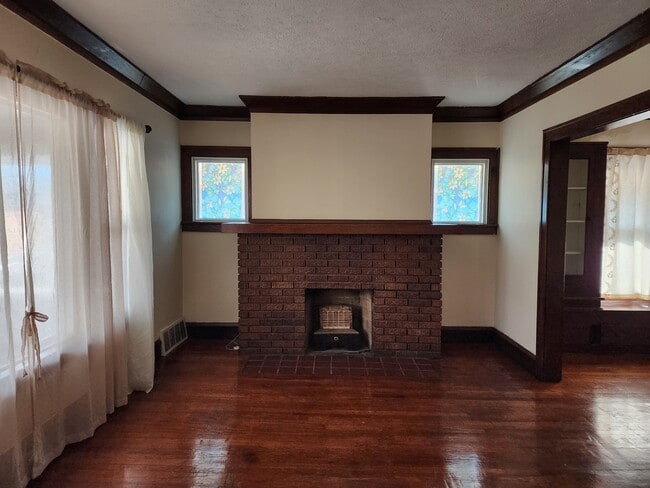 Sala de estar luminosa y acogedora con pisos de madera y chimenea decorativa. - 1382 Webb Rd Unidad 1382 Webb RD