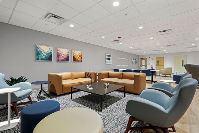 Modern resident lounge area with chic leather sofas, stylish armchairs, and vibrant abstract art on the walls.