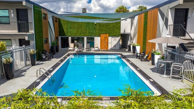Experience a refreshing retreat at our beautifully designed pool area. Featuring sleek design, comfortable lounge seating, and vibrant landscaping, it's your go-to spot for unwinding or soaking in the Florida sun. - Elon Winter Park Apartments