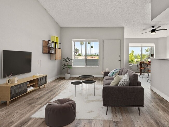 Sala de estar con piso de madera, amplios ventanales y vista al comedor.