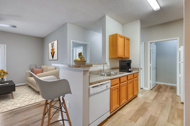 Kitchen and dining area at Dunwoody Place with light wood cabinetry, modern appliances, bar seating, and open sightlines to the living space in an income-restricted apartment home in Huntsville, Alabama.