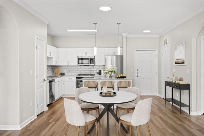 Dining area with an open kitchen, island seating, and bright finishes that create a welcoming setting for shared meals and everyday living.
