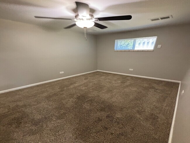Inviting bedroom with fresh beige carpet, cozy atmosphere, and a modern ceiling fan for perfect comfort. - Redwood Apartments