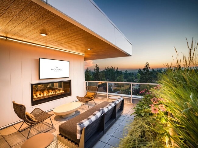 Take in the sunset from Modera Shoreline’s rooftop terrace, featuring a cozy fireplace, lush greenery, and breathtaking views of the Pacific Northwest. - Modera Shoreline