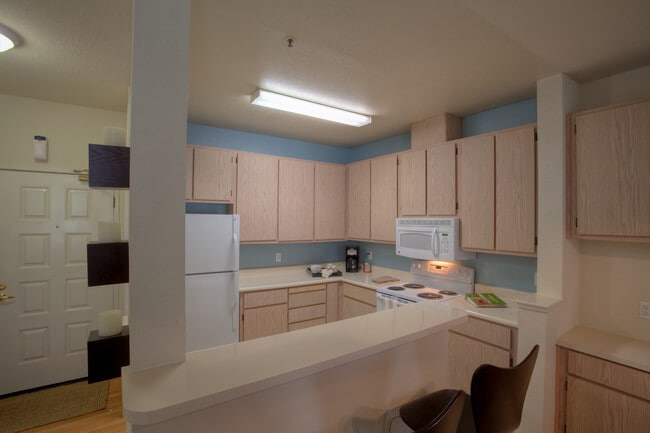 Classic Package I kitchen with light oak cabinetry, white laminate countertops, white appliances, and hard surface flooring