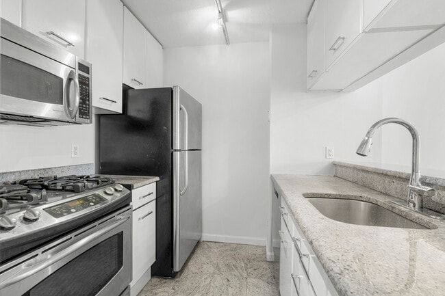 Kitchen with stainless steel appliances, granite counters, white cabinets with new drawer pulls. - 4 Martine Ave Unit 404
