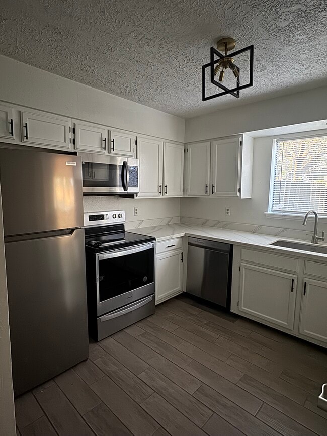 Modernized kitchen with quartz countertops, sleek cabinetry, and updated stainless-steel appliances. - 10038 Spring Place Dr