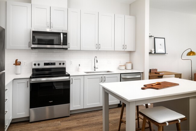 New West Phase apartments - Finish Package III Kitchen with stainless steel appliances, white quartz countertops, grey cabinetry, pendant lighting, and hard surface flooring - Avalon Hunt Valley and Hunt Valley West Apartments