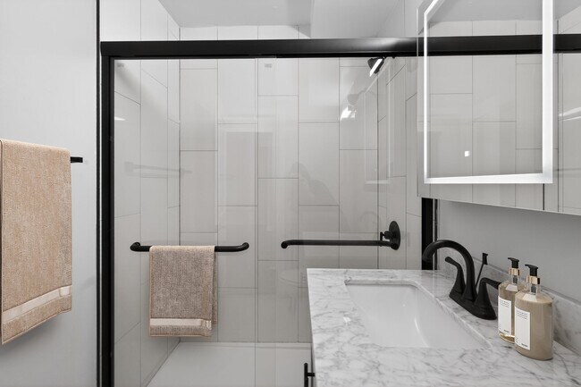 Elevate your living at Eagle Rock Apartments at Woodbury. This stunning, modern bathroom features sleek finishes and a spacious layout, perfect for relaxation. Don’t miss out on your ideal home—schedule a tour today!