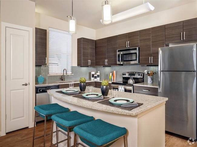 Kitchen with granite countertops, stainless steel appliances, wood-style floors, and modern lighting over island - Thirty Oaks Rental