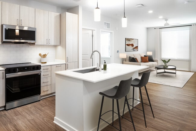 Design Collection II kitchen with stainless steel appliances, cream quartz countertops, oak cabinetry, and hard surface flooring
