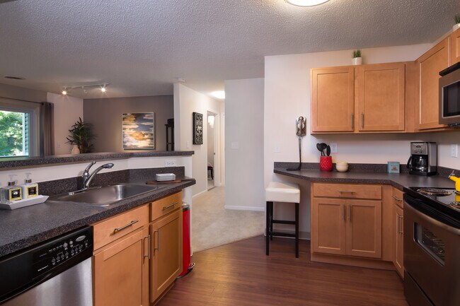 Classic Package kitchen with stainless steel appliances, black speckled laminate countertops, maple cabinetry and hard surface flooring