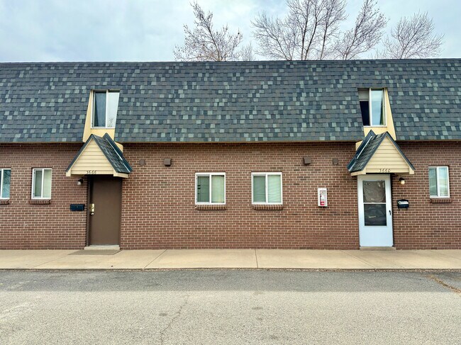 Front View Charming brick duplex with unique triangular roof accents and modern window design, perfect for cozy living. - 3650 Upham
