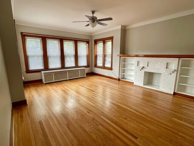 Living room with built in bookshelves and ornamental fireplace - 5336 W Dakin St Unit 1st Floor