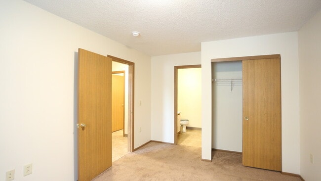 Carpeted bedroom, closet, and attached bathroom of a River Valley apartment home in Lancaster, OH.