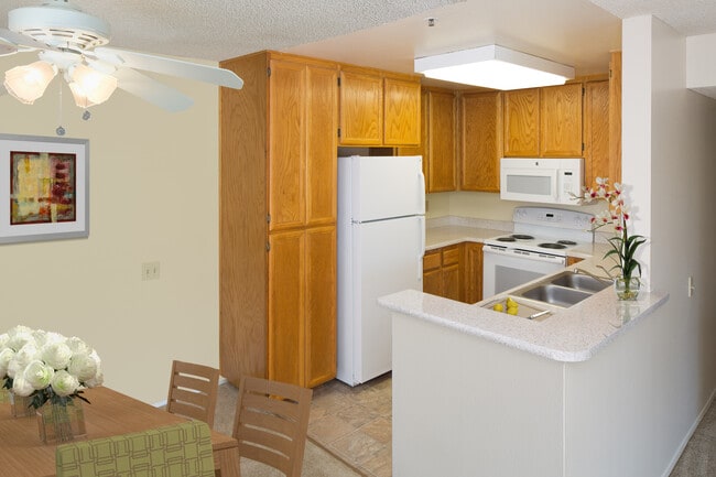 Classic Package kitchen with oak cabinetry, beige speckled laminate countertops, tile flooring, and white appliances