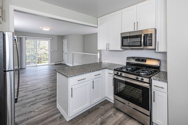 Newly renovated open kitchen featuring stainless steel appliances, granite counter tops and modern white cabinets.