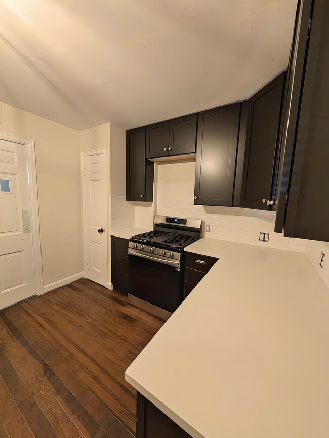 Cocina reformada con cocina de gas, encimeras de cuarzo y armarios negros. - 2734 N Avondale Blvd