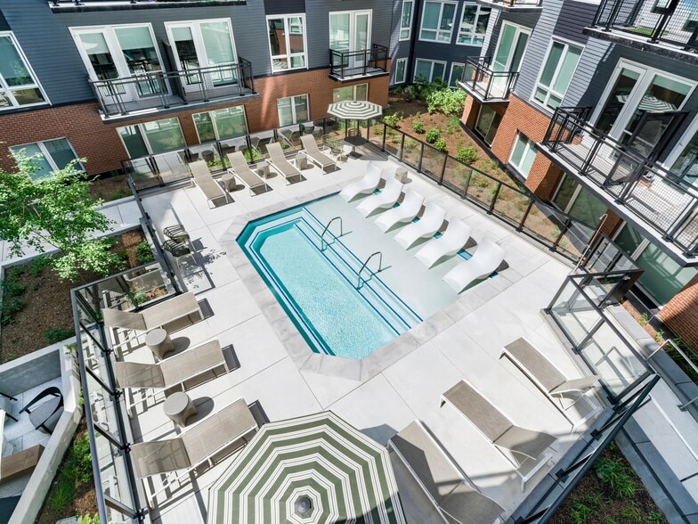 Courtyard pool with in-water loungers, sun seating, and surrounding balconies creating a social outdoor setting for warm-weather downtime.