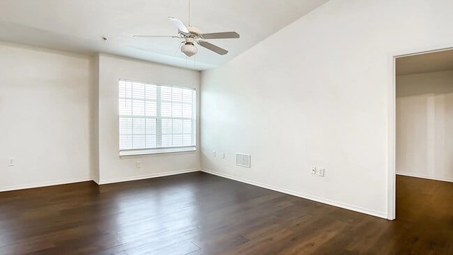 Live large and luxurious in your generous living area, where dark wood-style floors, a comforting ceiling fan, and a sizable window combine to create an inviting sanctuary. - Charleston Cay