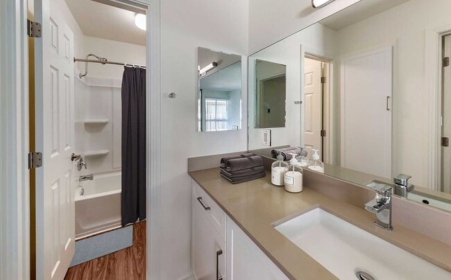 Renovated Package I bath with beige quartz countertops, new white cabinetry, and hard surface flooring