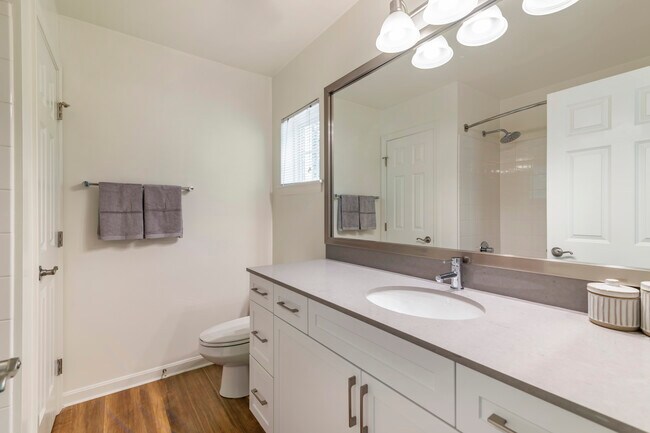 Renovated Package II bath with white cabinetry, grey quartz countertop, and hard surface flooring