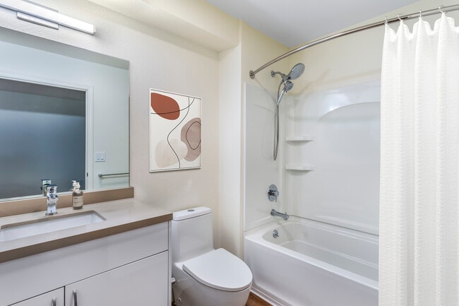 Baño renovado Package II con encimeras de cuarzo beige, gabinetes blancos y pisos de superficie dura