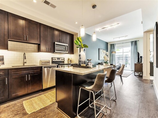 Amplia cocina con isla, con pisos de madera y gabinetes de color oscuro - Preston Hollow Village