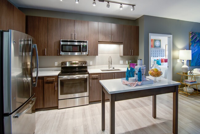 Open concept kitchen with quartz stone countertops, stainless-steel appliances, kitchen island and hard surface flooring