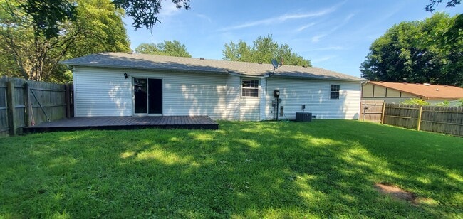 Fenced backyard with deck and mature trees. - 313 Britanna Dr