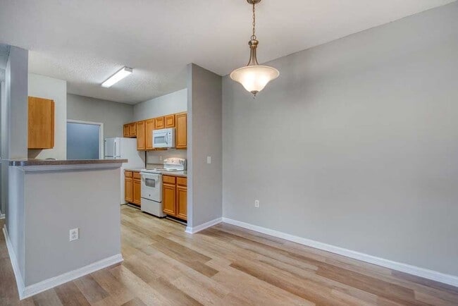 Kitchen and dining view with breakfast bar, wood cabinets, white appliances, laminate counters, and open floor plan