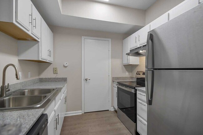 Kitchen with white cabinets, stainless steel refrigerator, electric range, double sink, and wood style flooring throughout