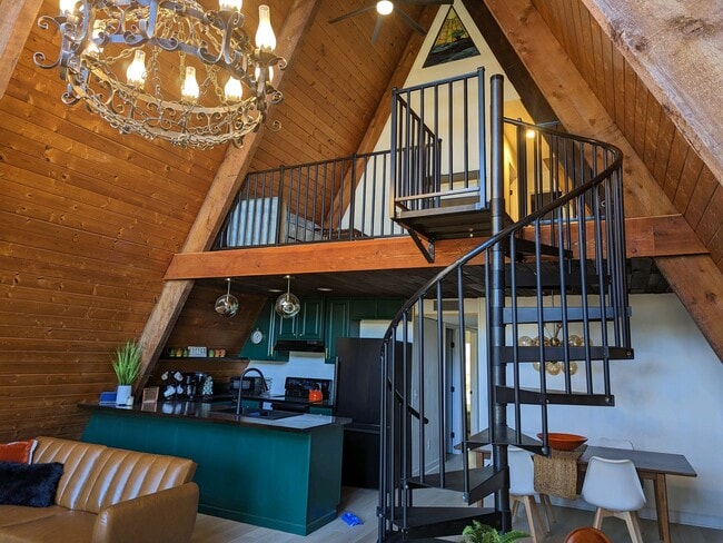 Un interior de concepto abierto con tonos cálidos de madera, una escalera de caracol que conduce a un loft y un baño completo. - 2406 Crockett Cir