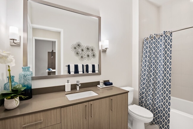 Bath with grey quartz countertop and hard-surface vinyl plank flooring