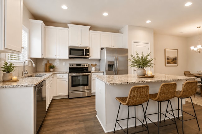 Spacious kitchen with an island, ample storage, stainless steel appliances and view into the living room.