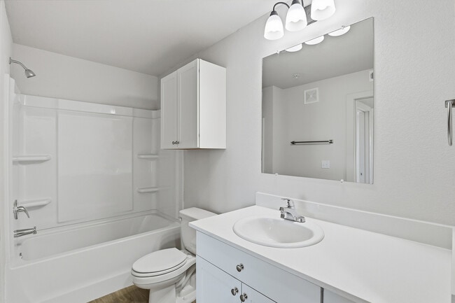 Pristine modern bathroom featuring sleek white cabinetry, elegant fixtures, and a spacious mirror, perfect for a contemporary living space.